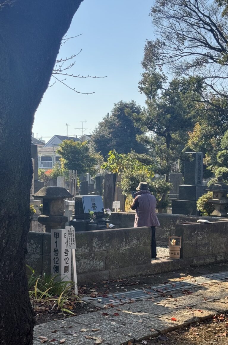 Cimetière avec une vieille dame qui nettoie une tombe.