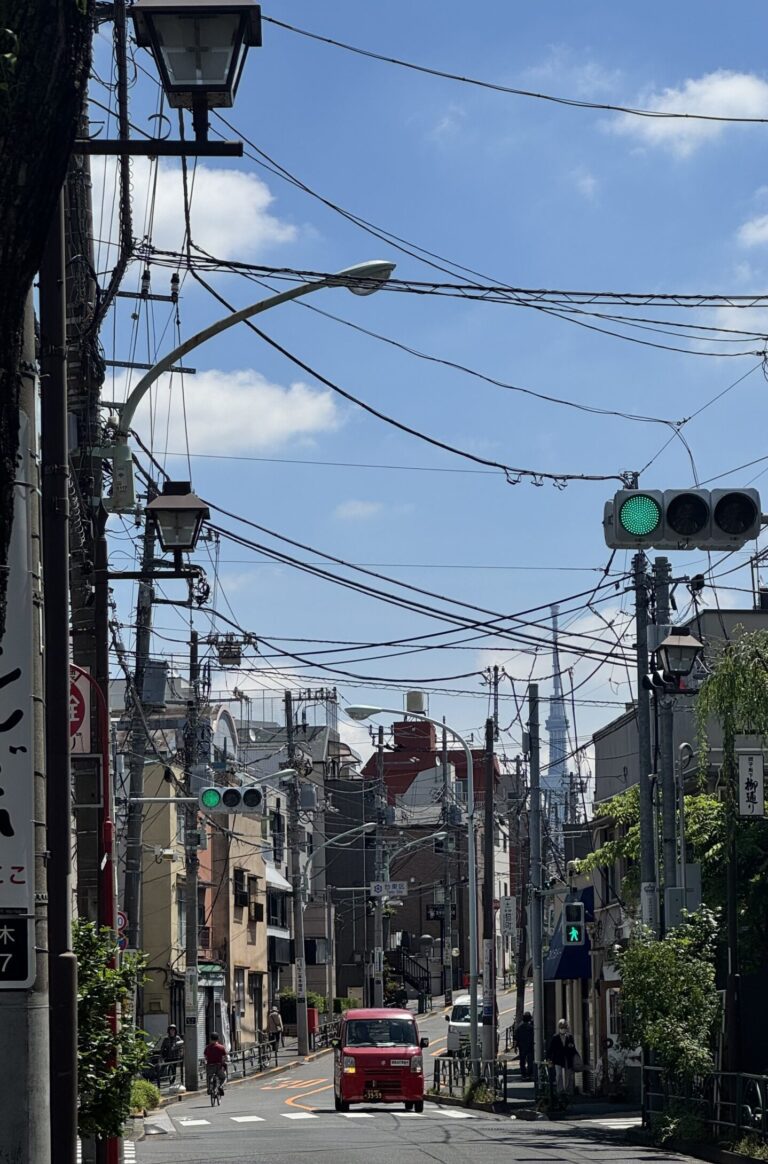 Rue vide avec cable electrique et une petite voiture rouge au milieu de la route.