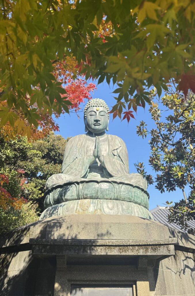 Buddha statue at Tennō-Ji temple in Yanaka during momiji season